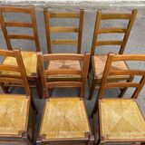 6 light solid wood chairs with high straw backs, farmhouse style.