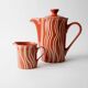 Vintage tea or coffee service in 1970s ceramic, teapot with lid and milk jug, rust orange with retro striped pattern, mid-century decoration, gift idea.