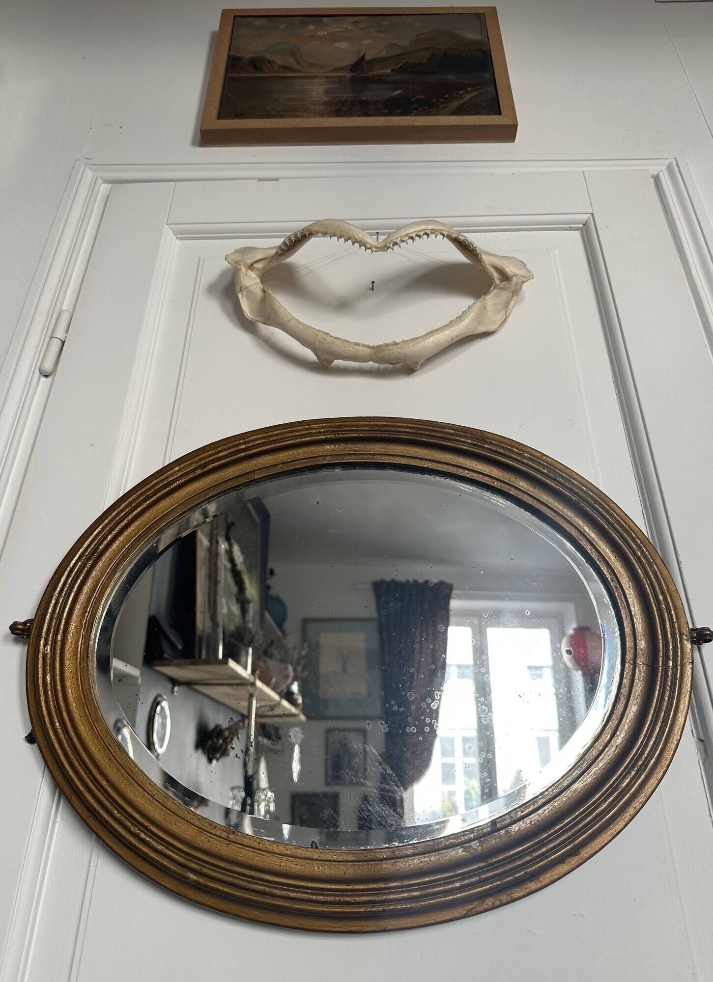 Antique oval mirror in gilded wood, bevelled mercury glass, 19th century.