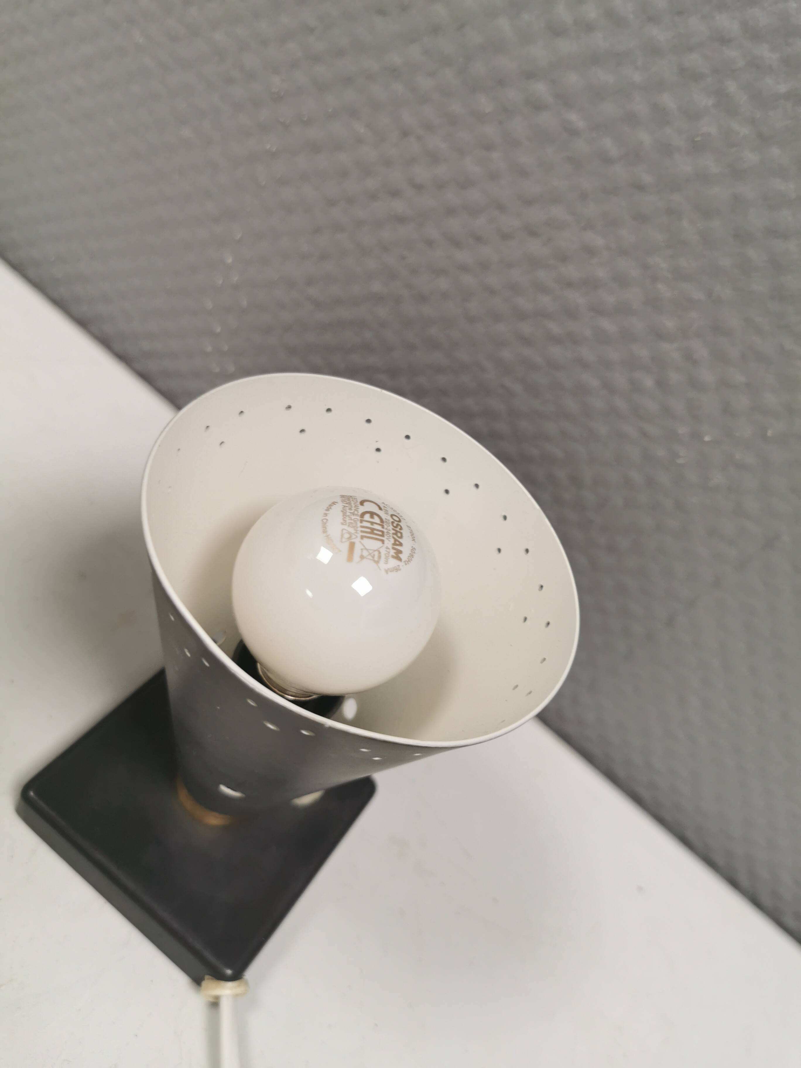 Small stylish table lamp with perforations and milky white opal glass shade