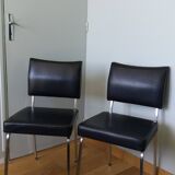 Chrome metal chairs and black faux leather upholstery in retro modernist style.