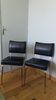 Chrome metal chairs and black faux leather upholstery in retro modernist style.