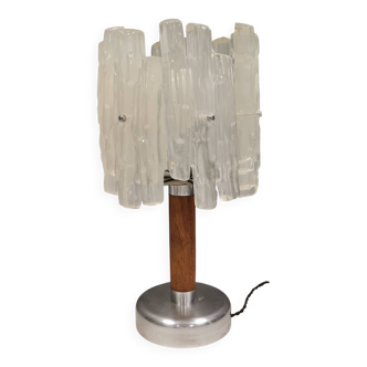 Lampe de table avec un « tronc » en teck, un pied en métal argenté et un abat-jour en acrylique.