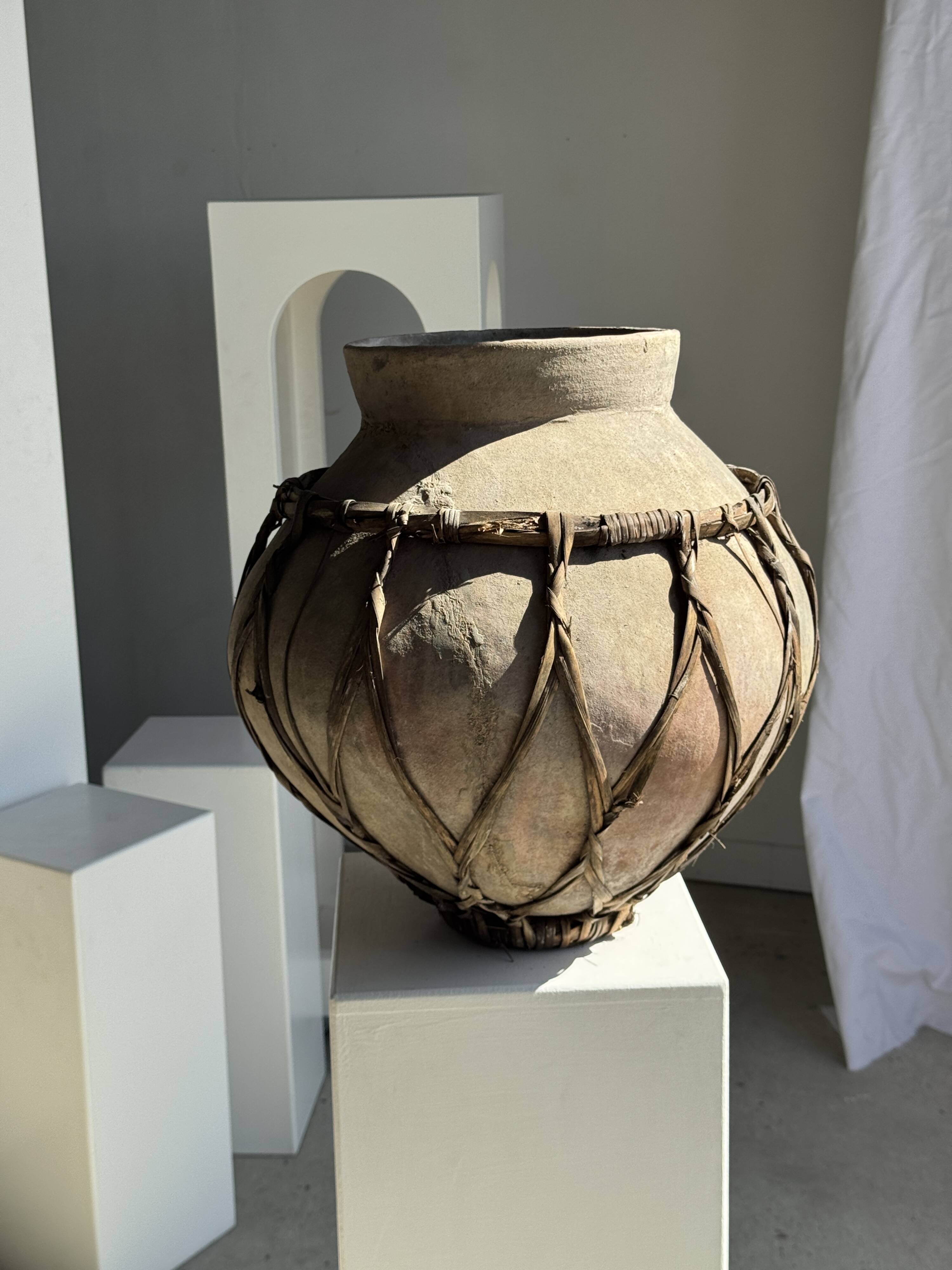 Very large light grey terracotta pot with handles and rattan crossbars.