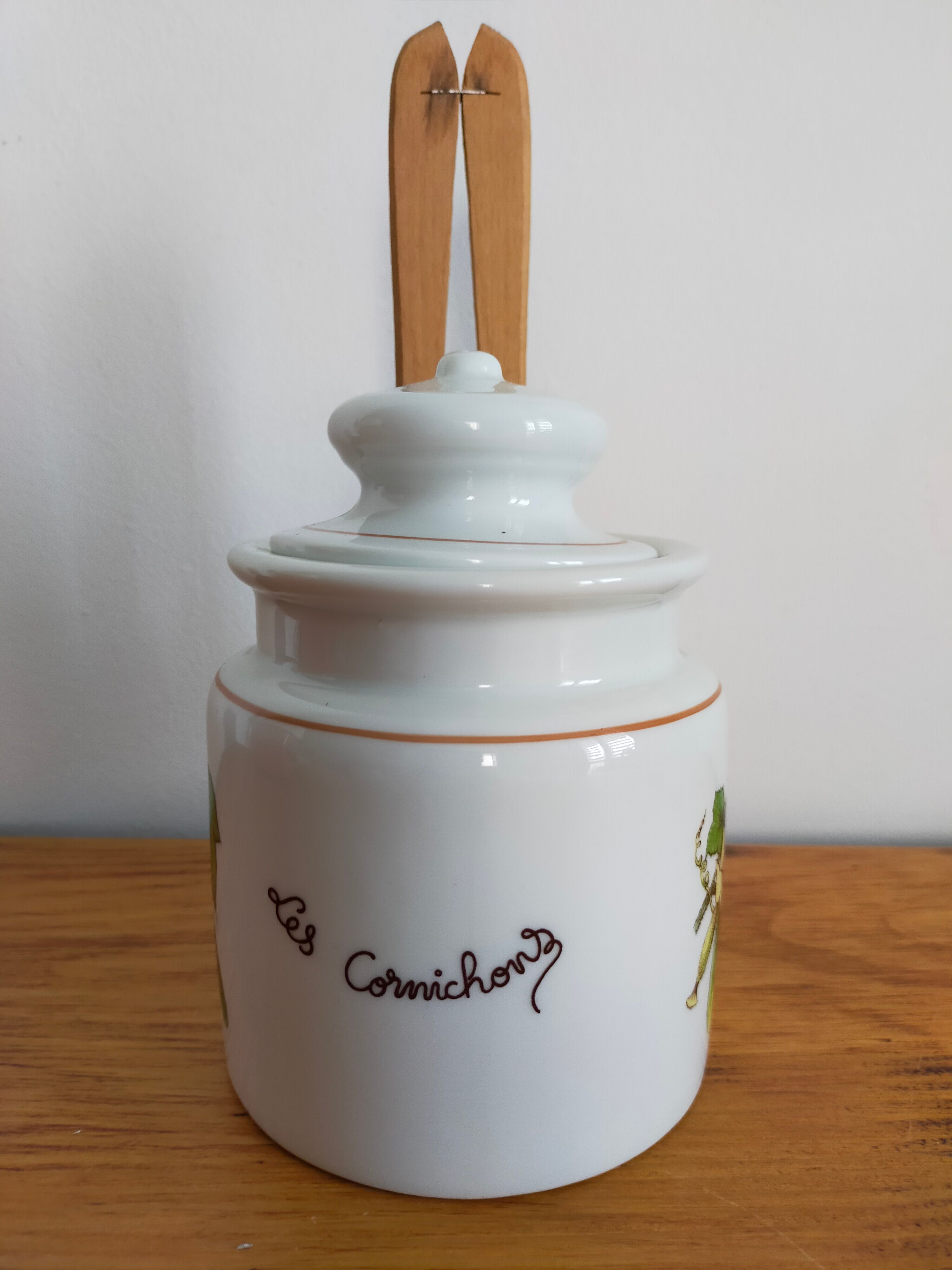 Vintage porcelain pickle pot with wooden pliers.