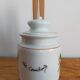 Vintage porcelain pickle pot with wooden pliers.