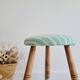 Antique tripod stool with striped seat.