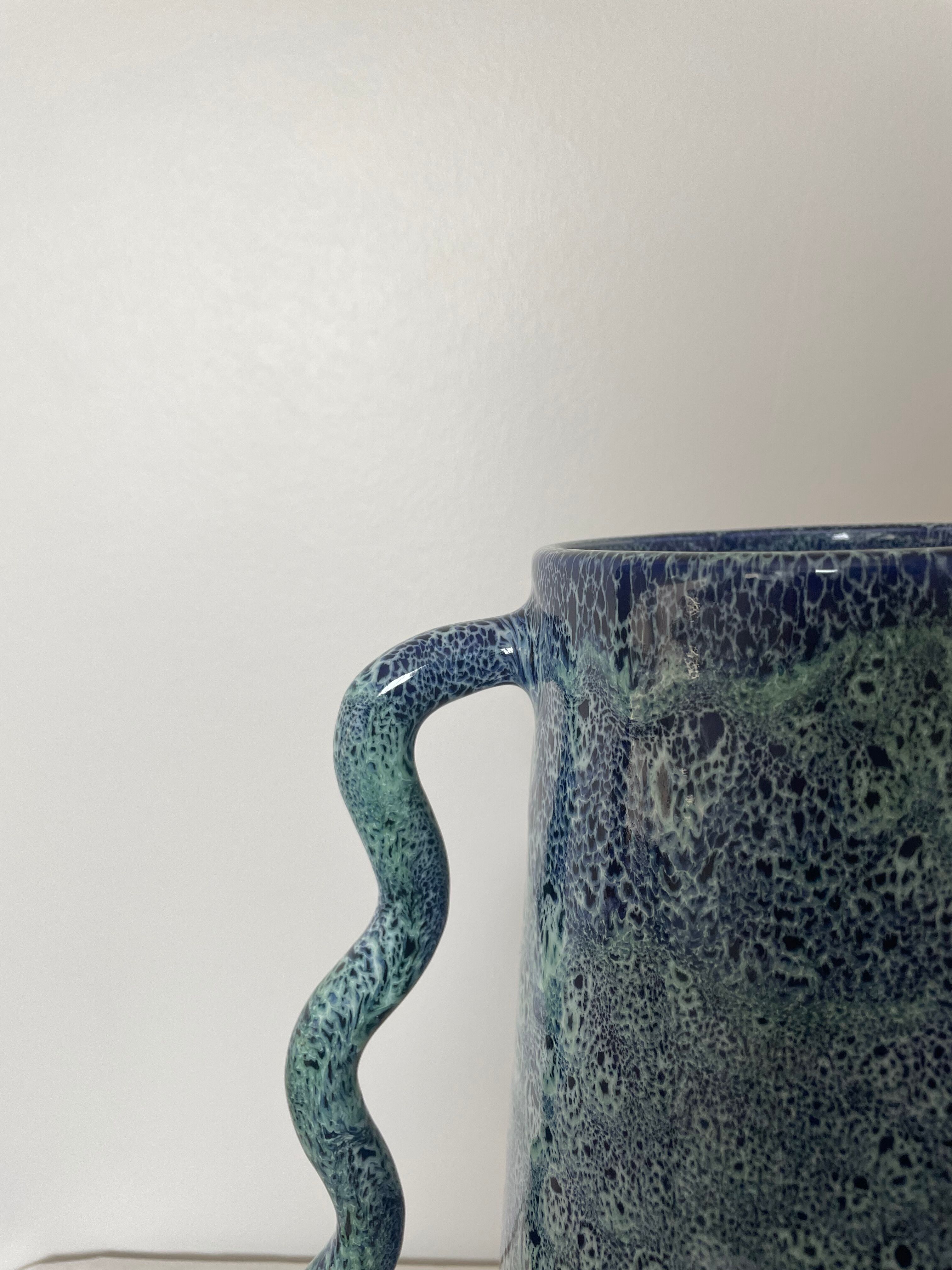Blue-green ceramic vase with abstract wavy handles