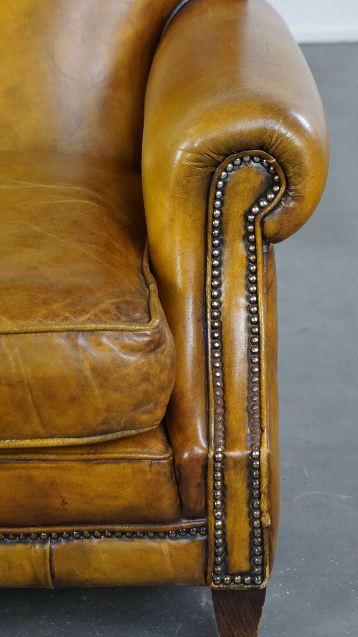 Comfortable large yellow English-style leather armchair with a fine finish and decorative nails