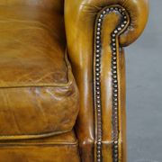 Comfortable large yellow English-style leather armchair with a fine finish and decorative nails