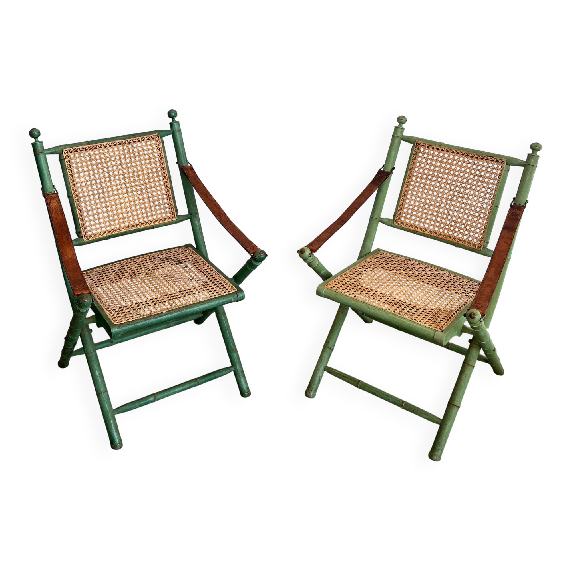 Paire de chaises safari pliantes façon faux-bambou patiné, dossiers et assises cannées et repose-bras en cuir