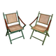 Paire de chaises safari pliantes façon faux-bambou patiné, dossiers et assises cannées et repose-bras en cuir