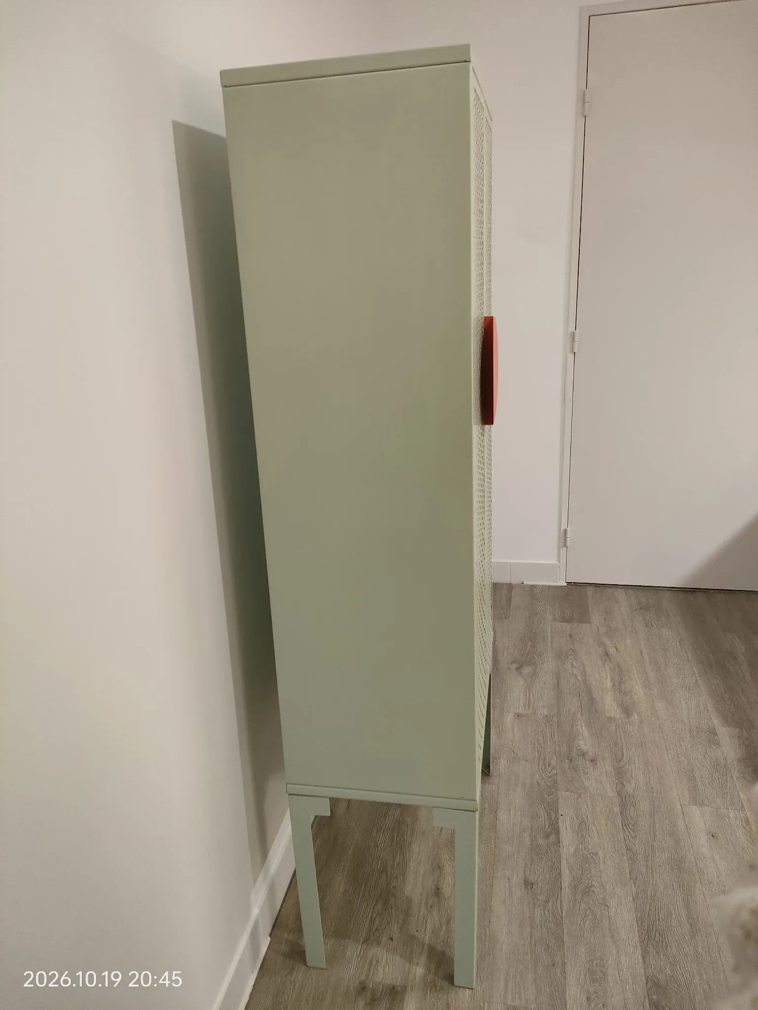 Vintage sage green metal wardrobe with louvered doors and coral handles.