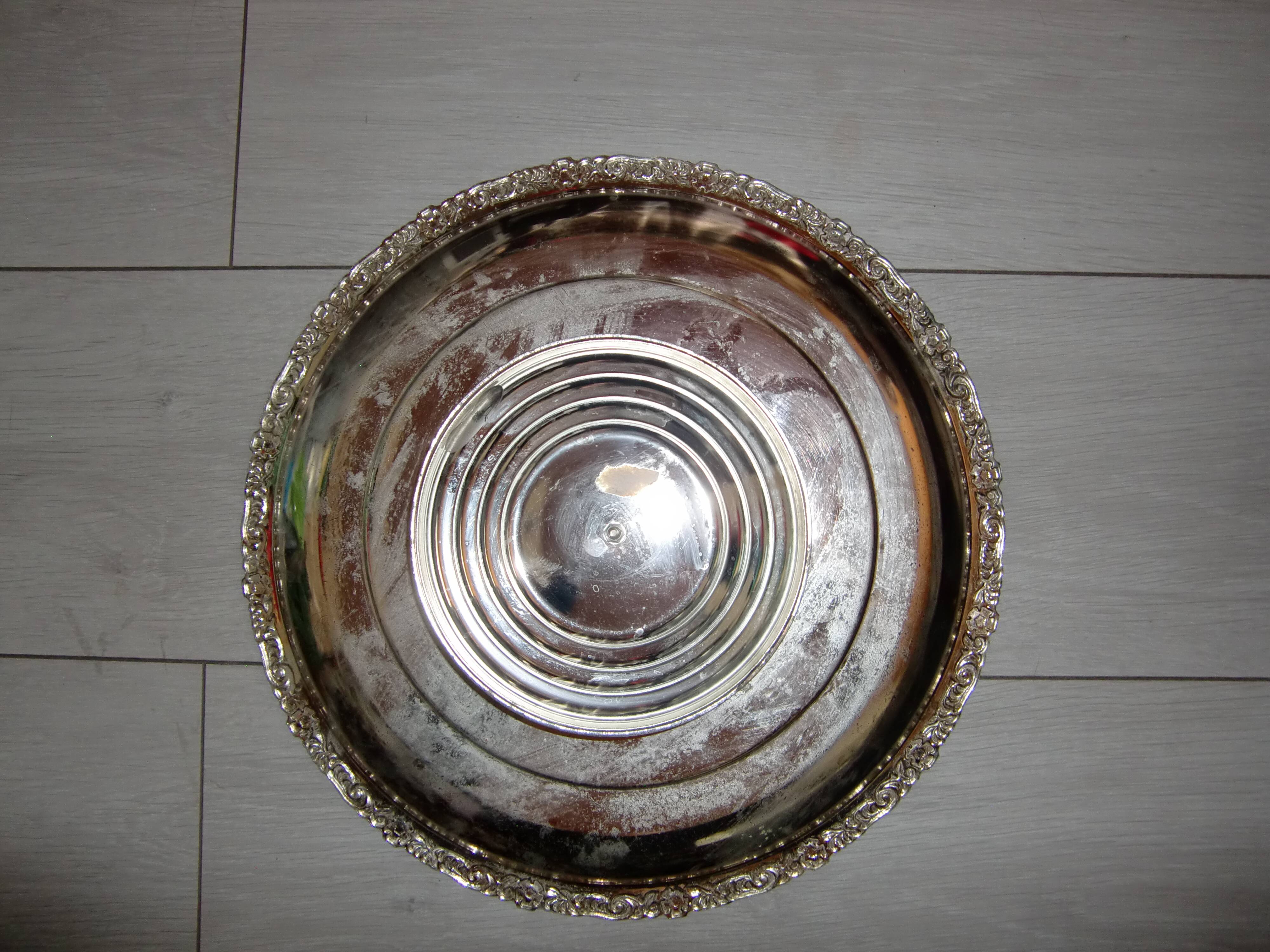 Large silver metal tray raised by a central foot