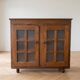Small antique wooden sideboard with glass doors.