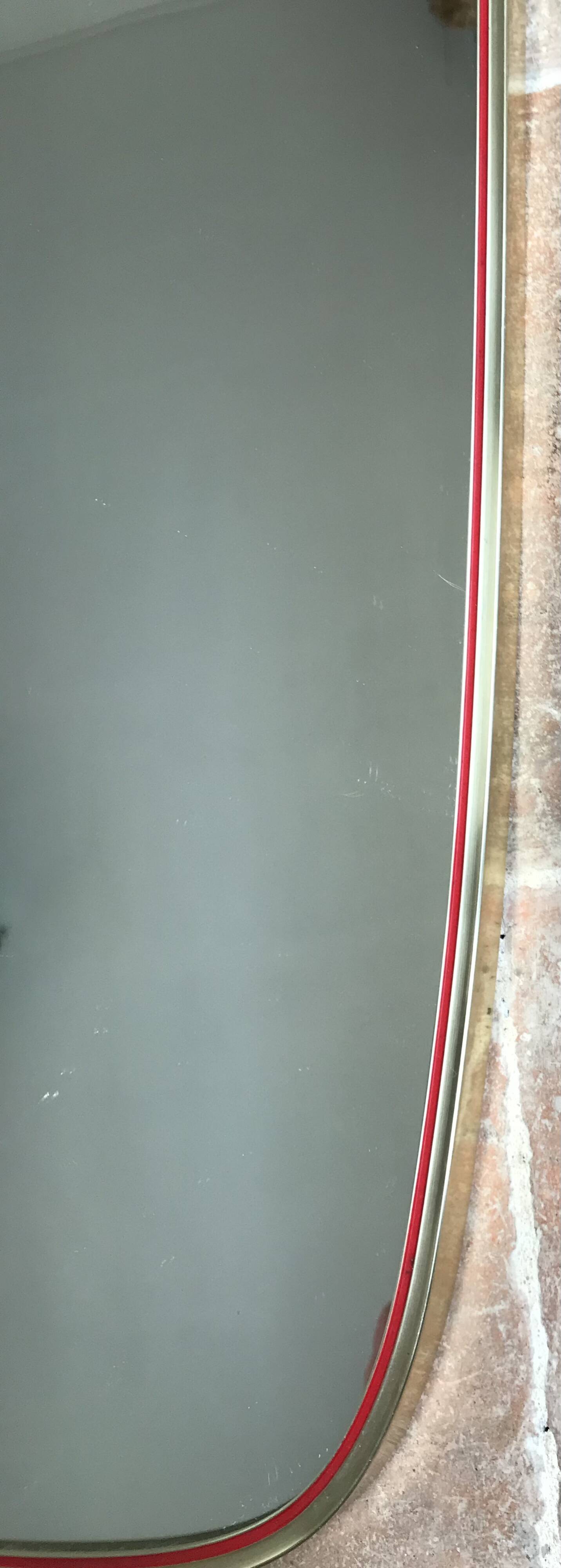 Vintage 1960s mirror in a freeform shape with a gold and red trim.