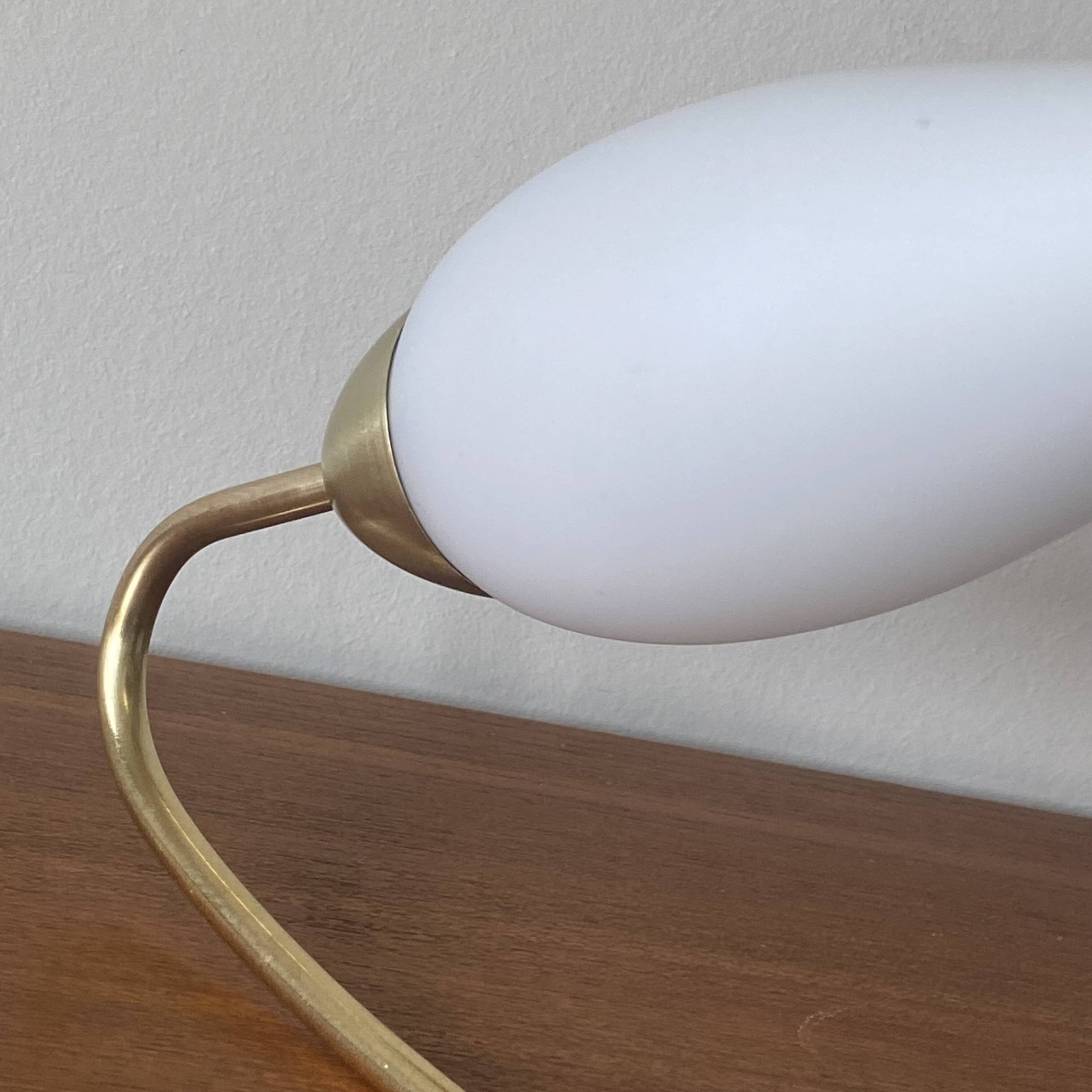 Swan neck wall light in brass and white opaline glass tulip.