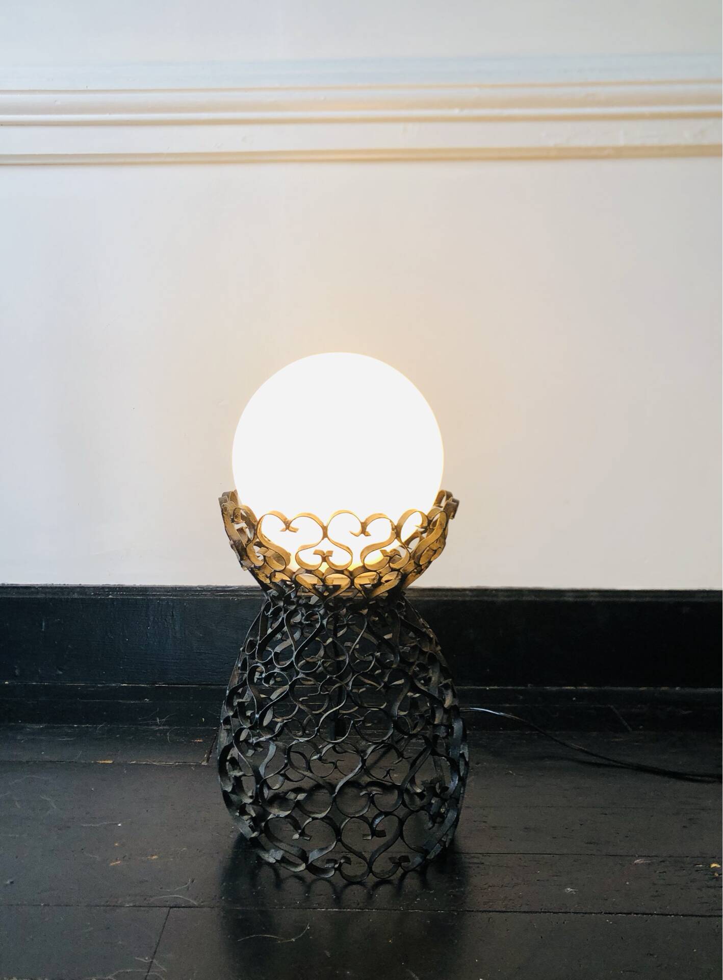 Handcrafted wrought iron lamp with a white opaline globe.