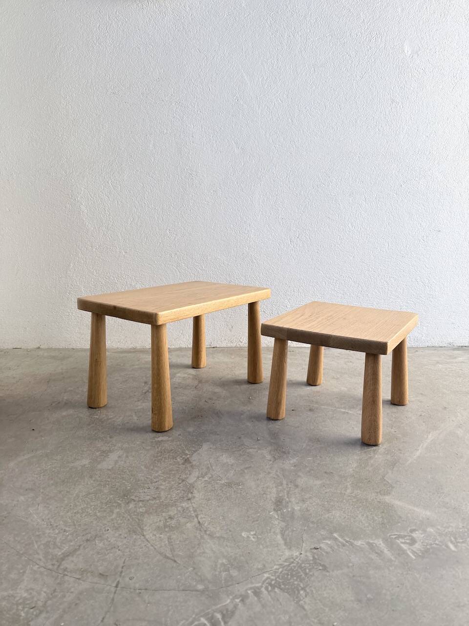 Two stools or small nesting tables in light oak.