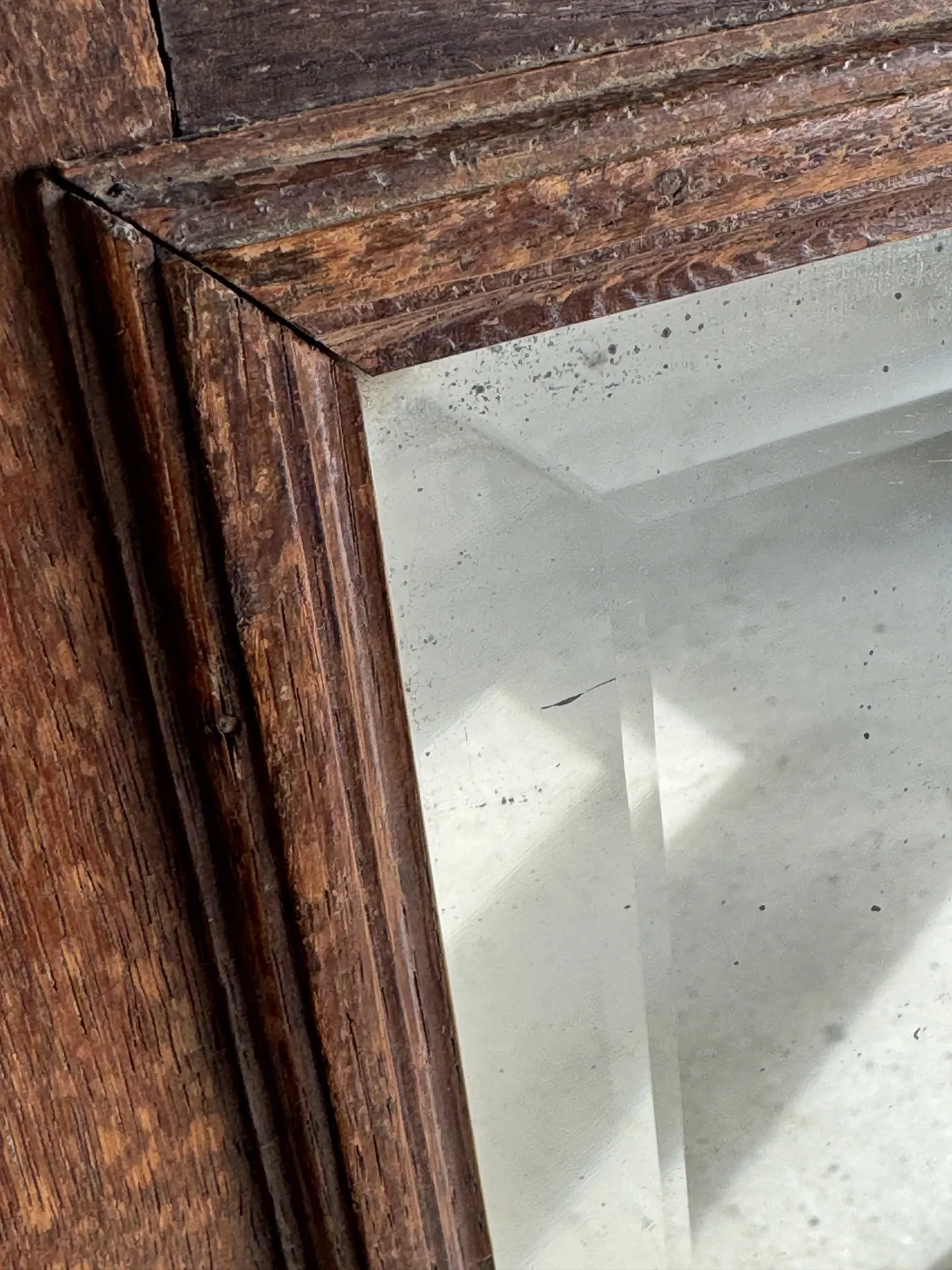 Antique mirror door (left) of a brown oak wardrobe with bevelled glass.