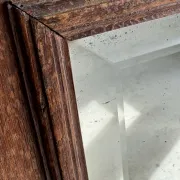 Antique mirror door (left) of a brown oak wardrobe with bevelled glass.