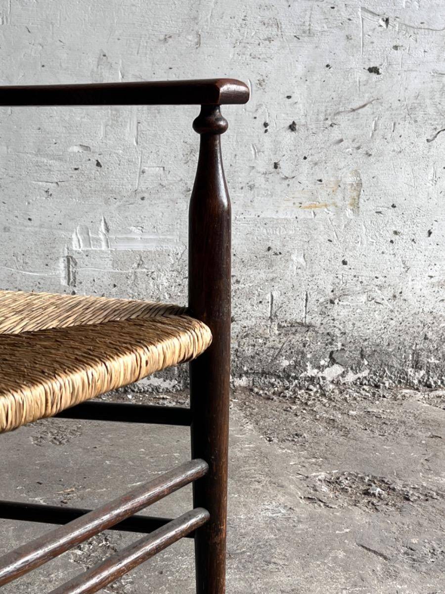 Dark brown solid wood Arts & Crafts armchair with natural rush seat and high back