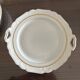 This dish appears to be a serving dish or a round plate with handles made of porcelain.