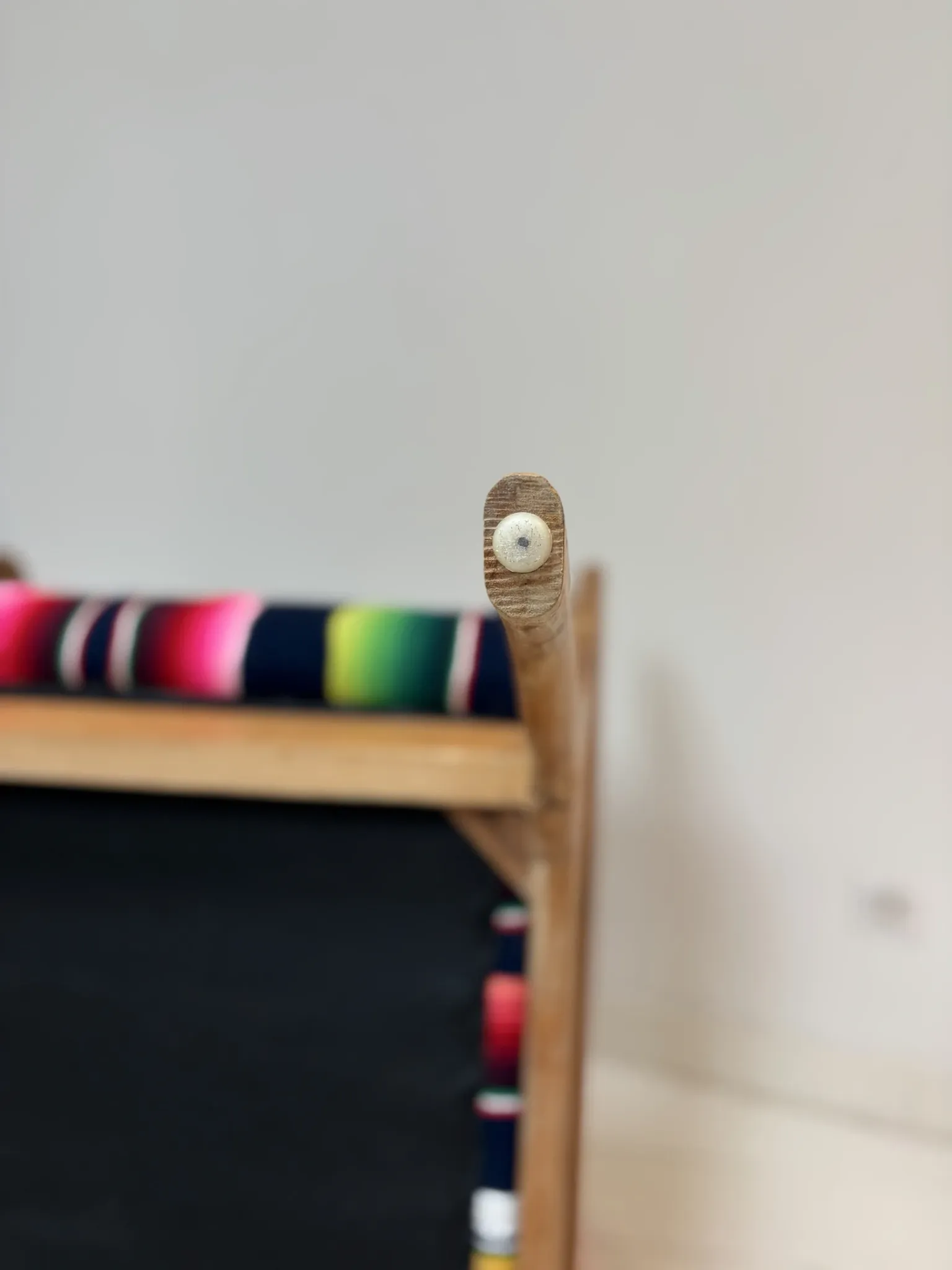 Scandinavian-style armchair in curved wood and colourful striped fabric.