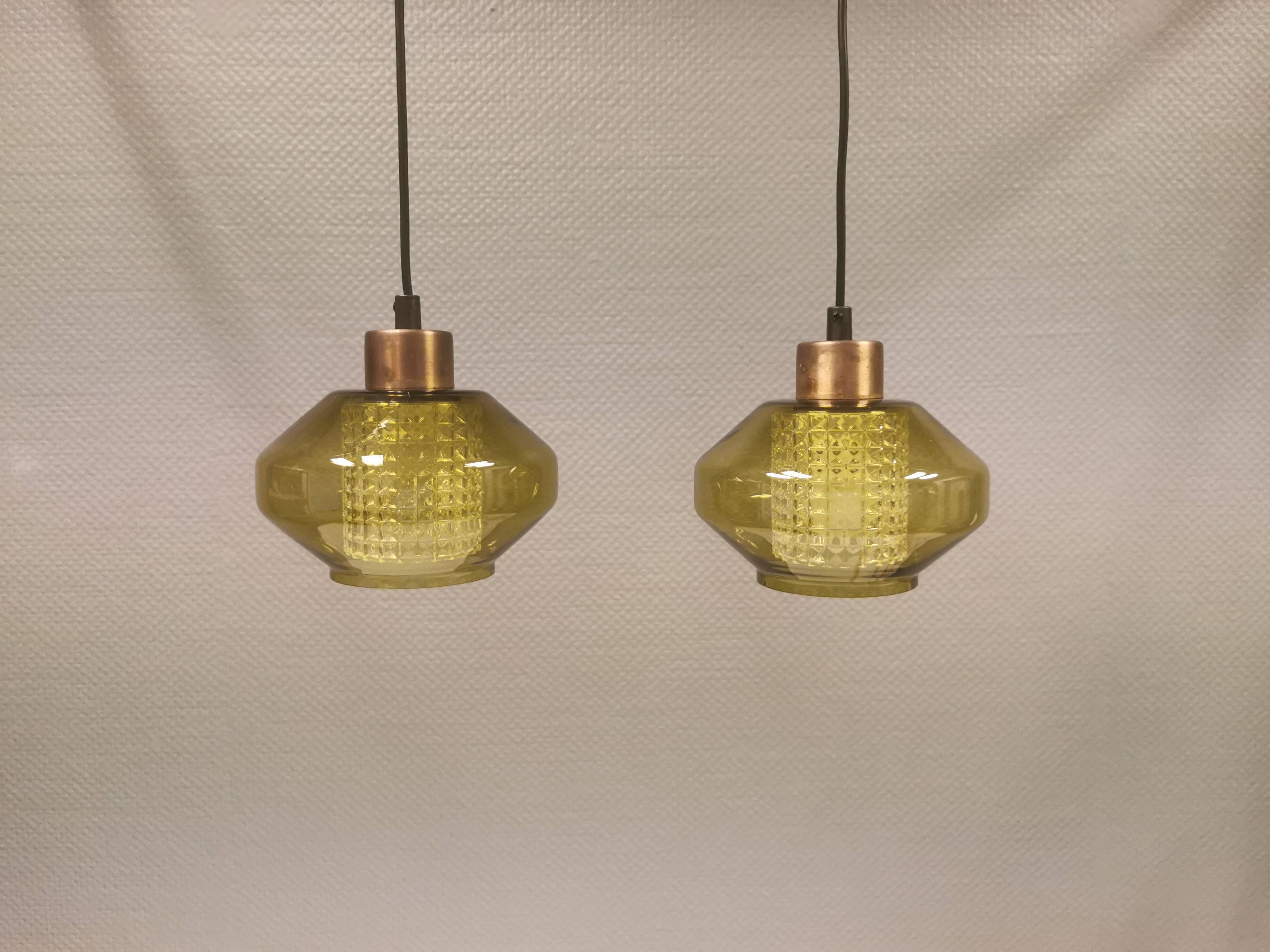 Hanging lamp with an outer shade of olive green glass and an inner shade of clear, crystal glass.