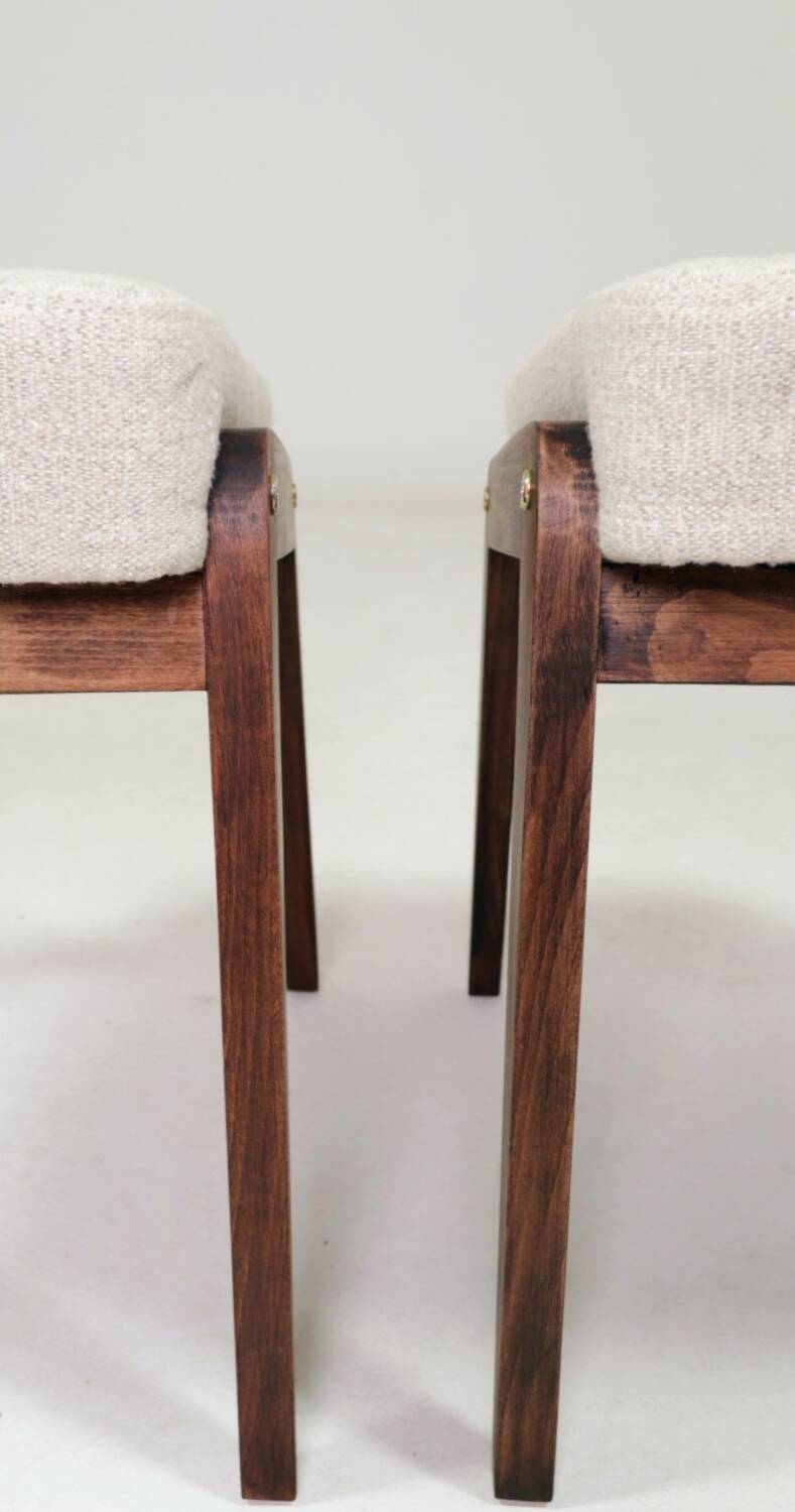 Pair of wooden stools with beige fabric.