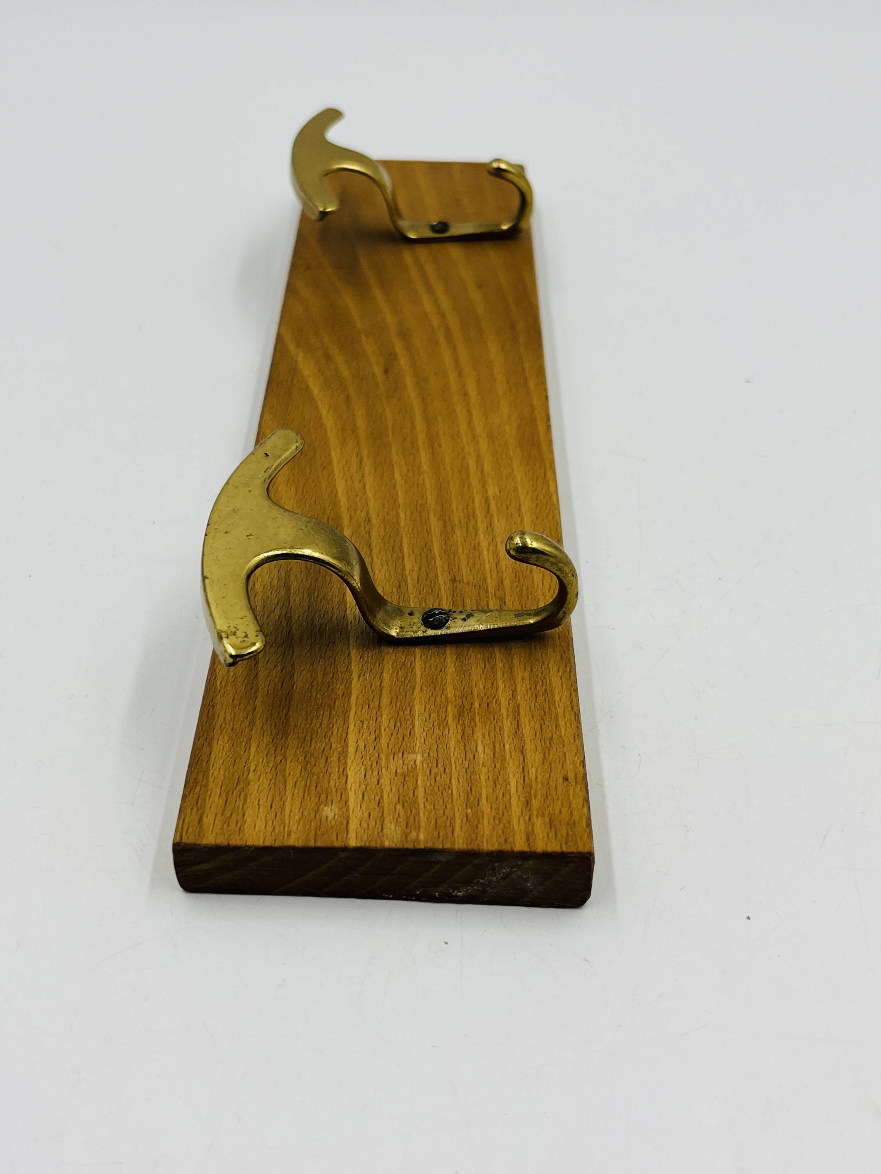 Vintage wall coat rack in brass and wood design.