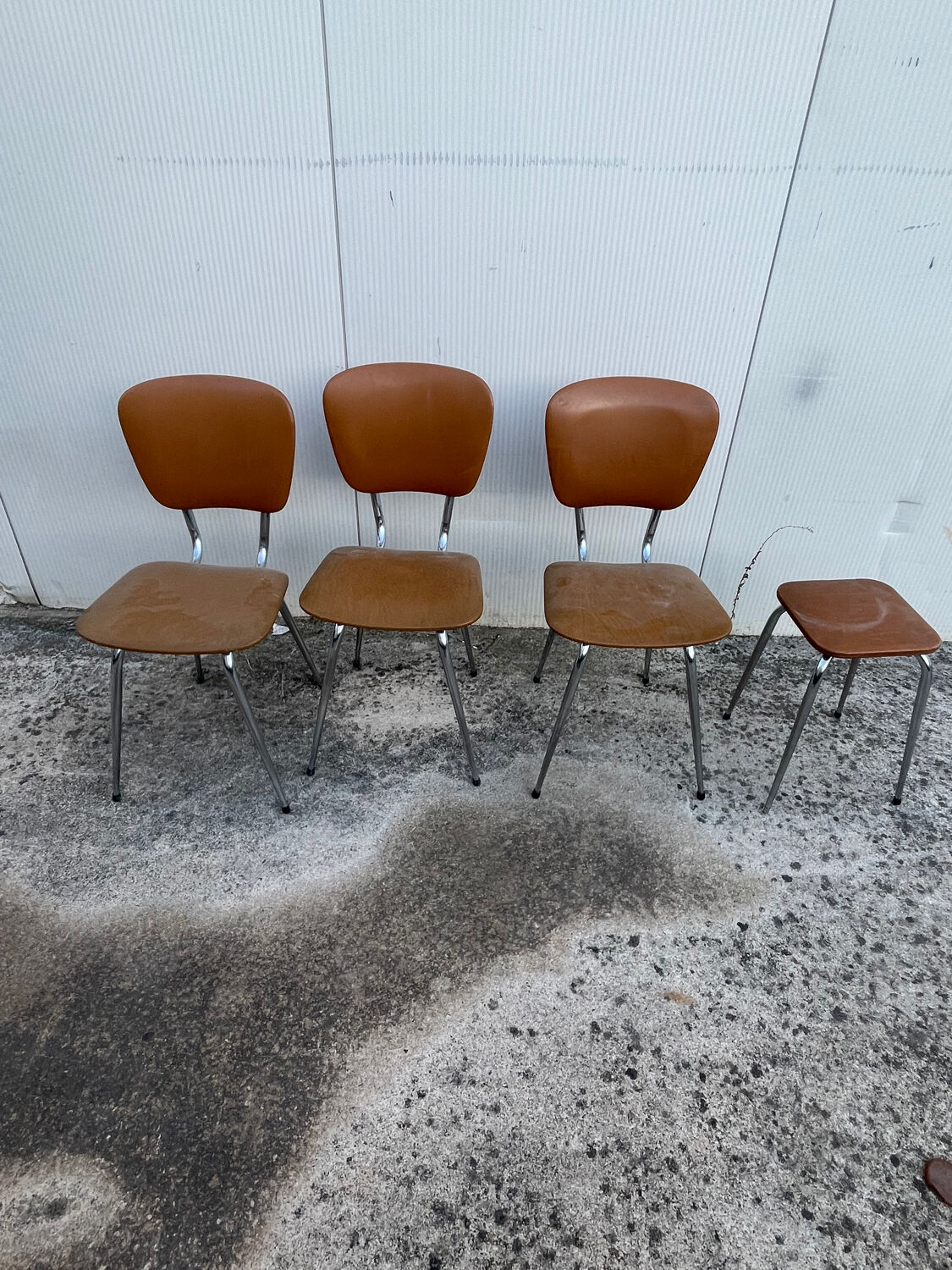 3 chairs and a vintage stool in faux leather and tubular design.