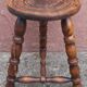Low wooden tripod stool.