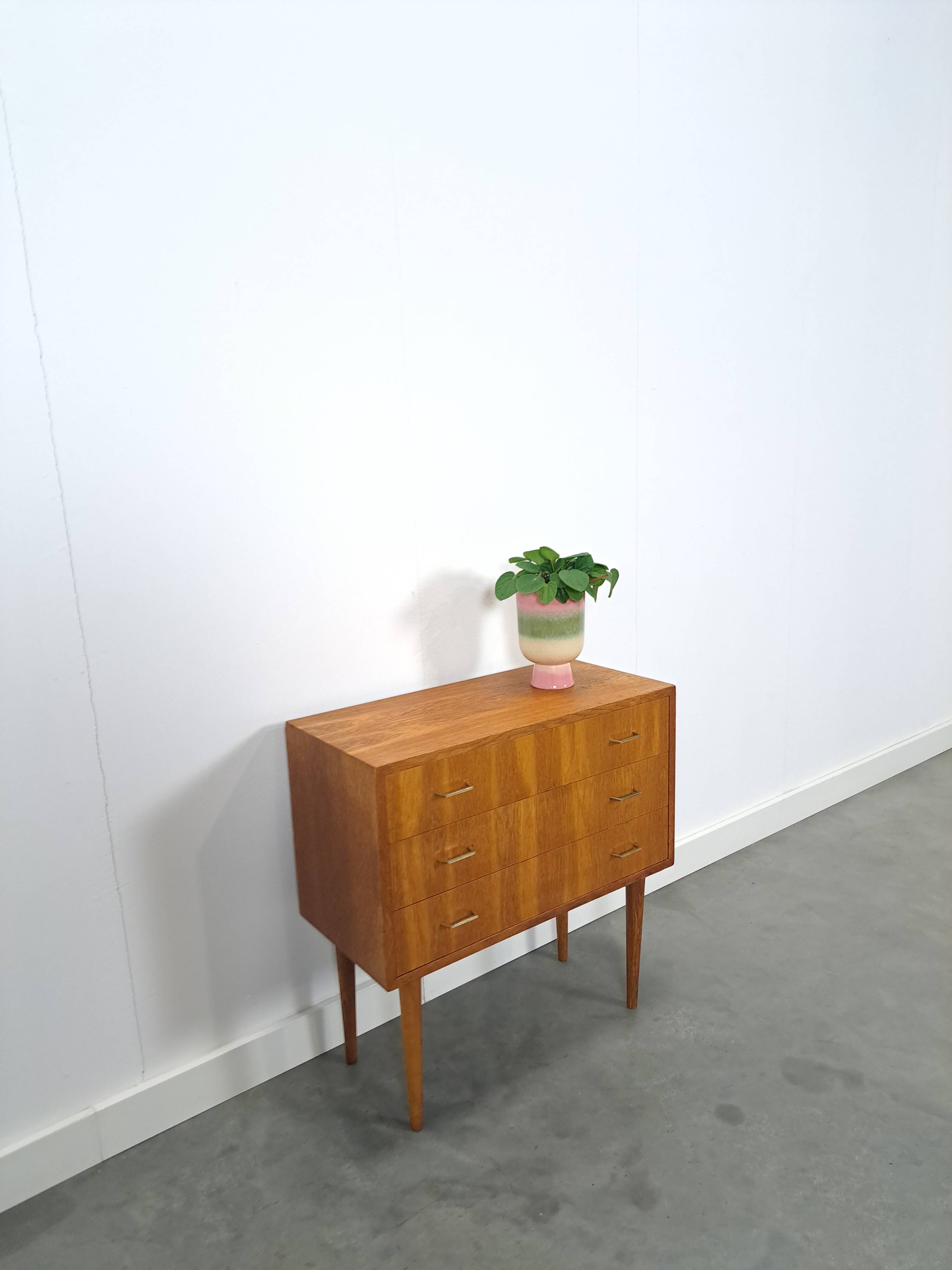 Commode danoise avec de hauts pieds et des poignées dorées.