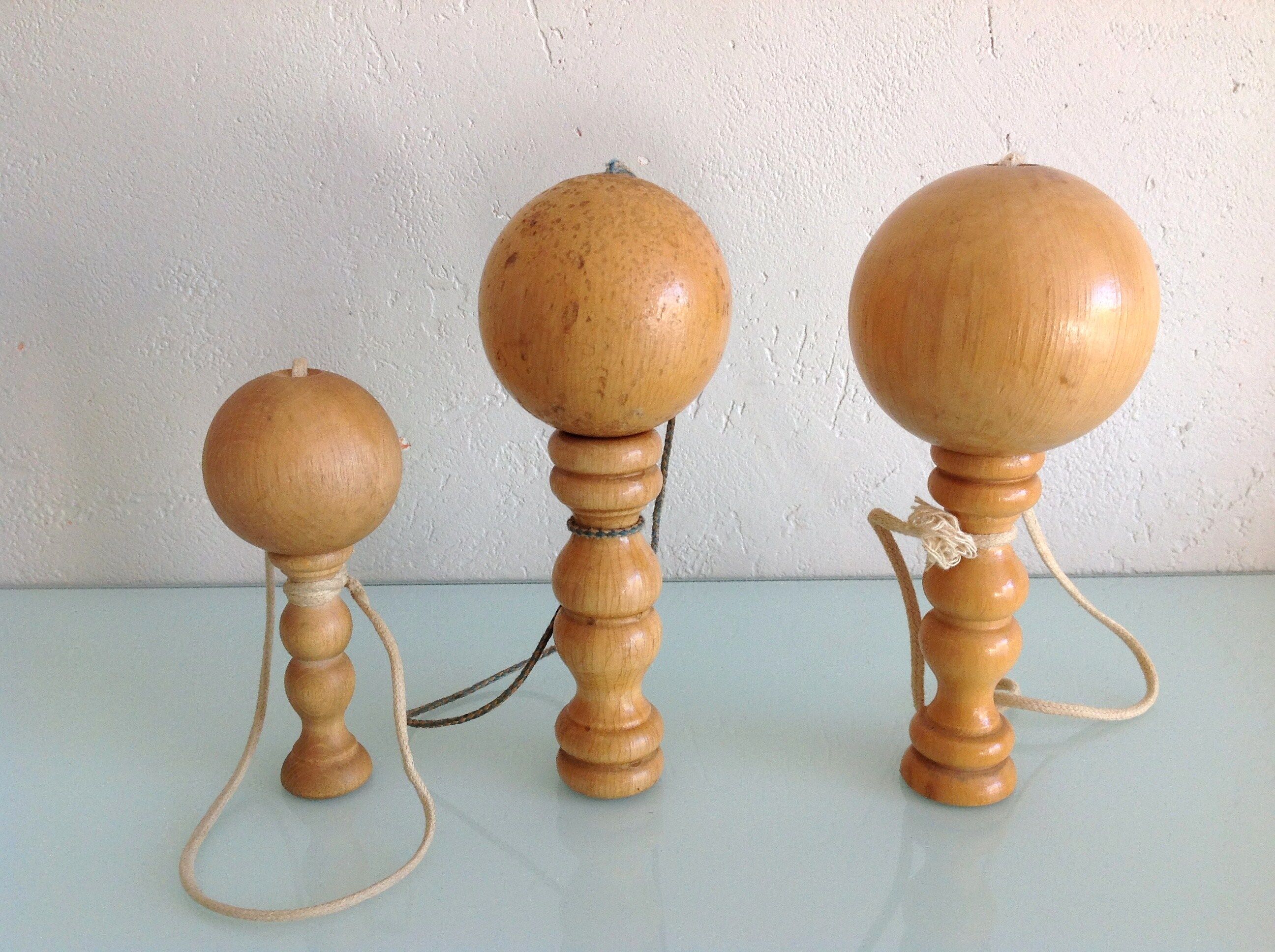 Suite de trois anciens bilboquets en bois clair