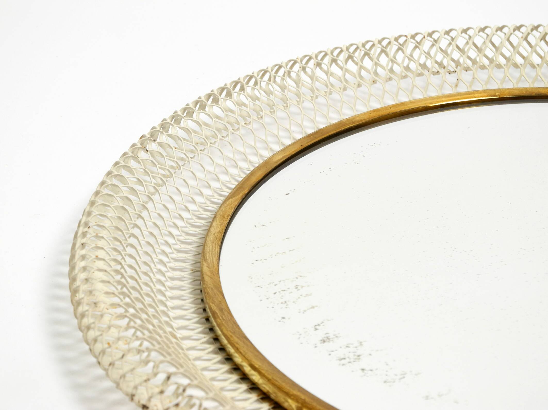 Mid Century Modern round wall mirror with a white expanded metal frame
