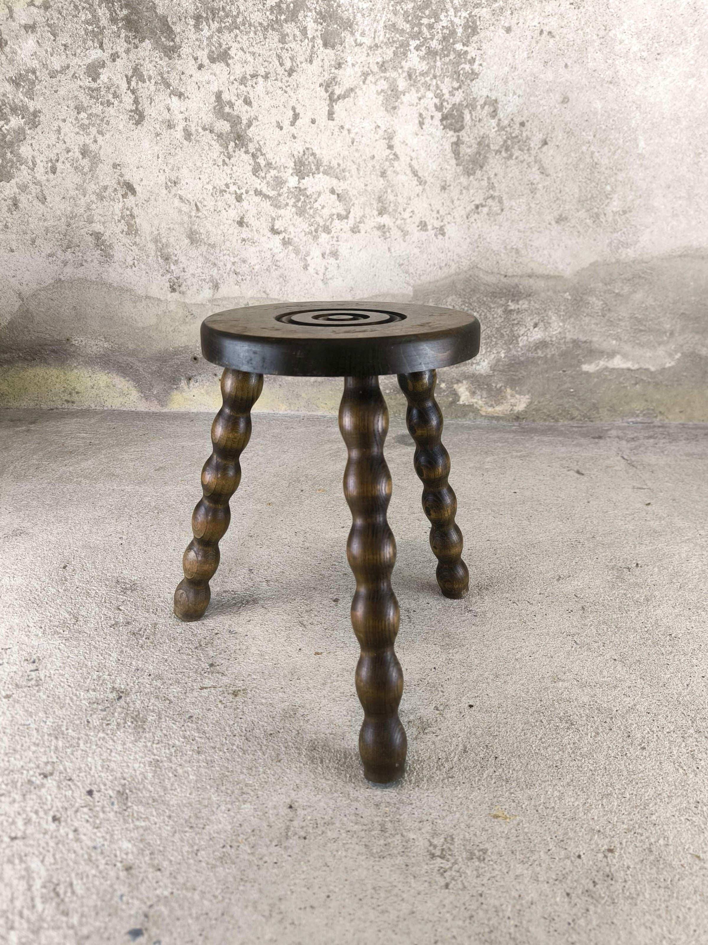 Small three-legged wooden stool with beaded feet.