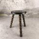 Small three-legged wooden stool with beaded feet.