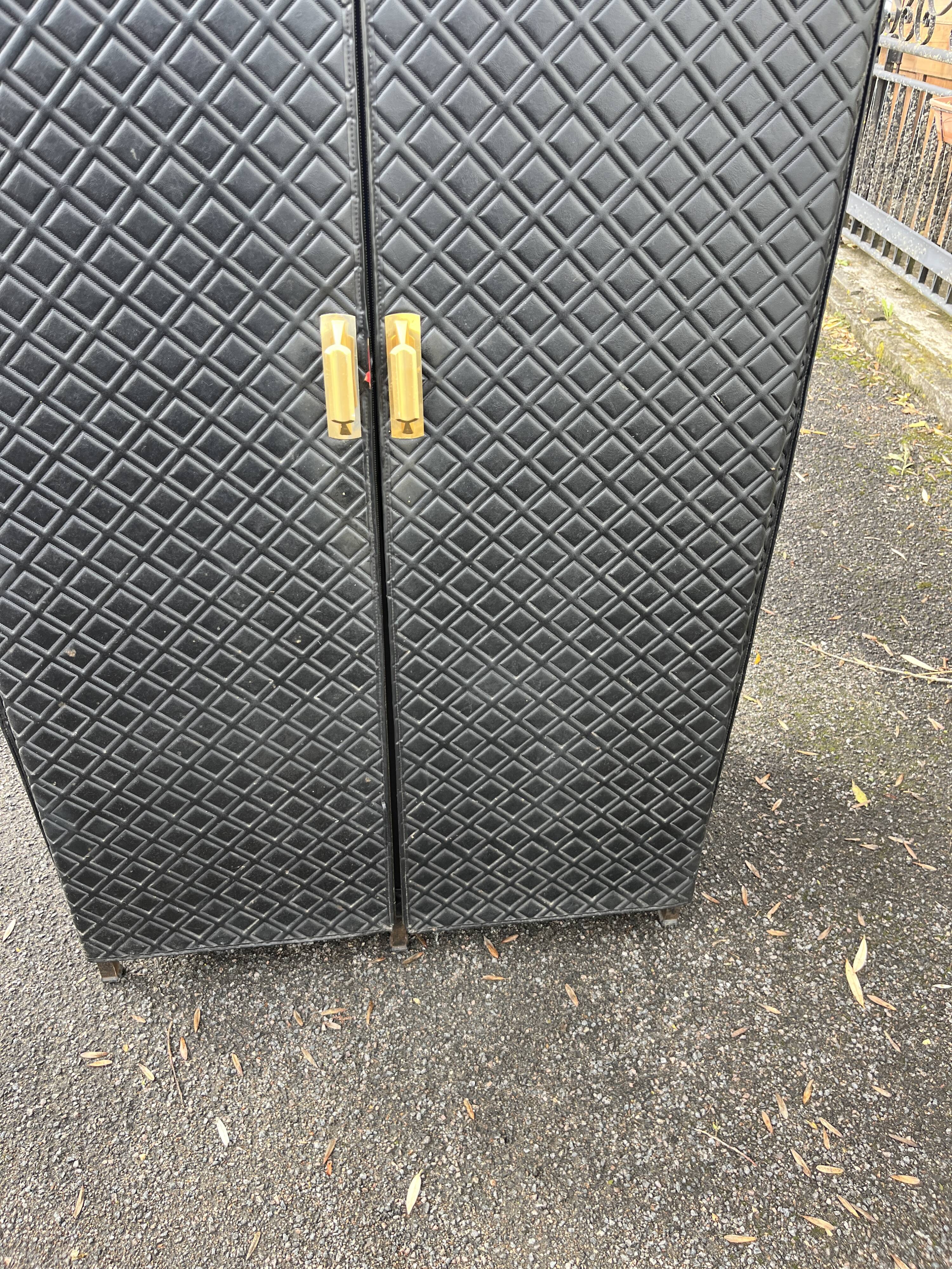 Contemporary wardrobe in black faux leather with diamond pattern and gold handles.