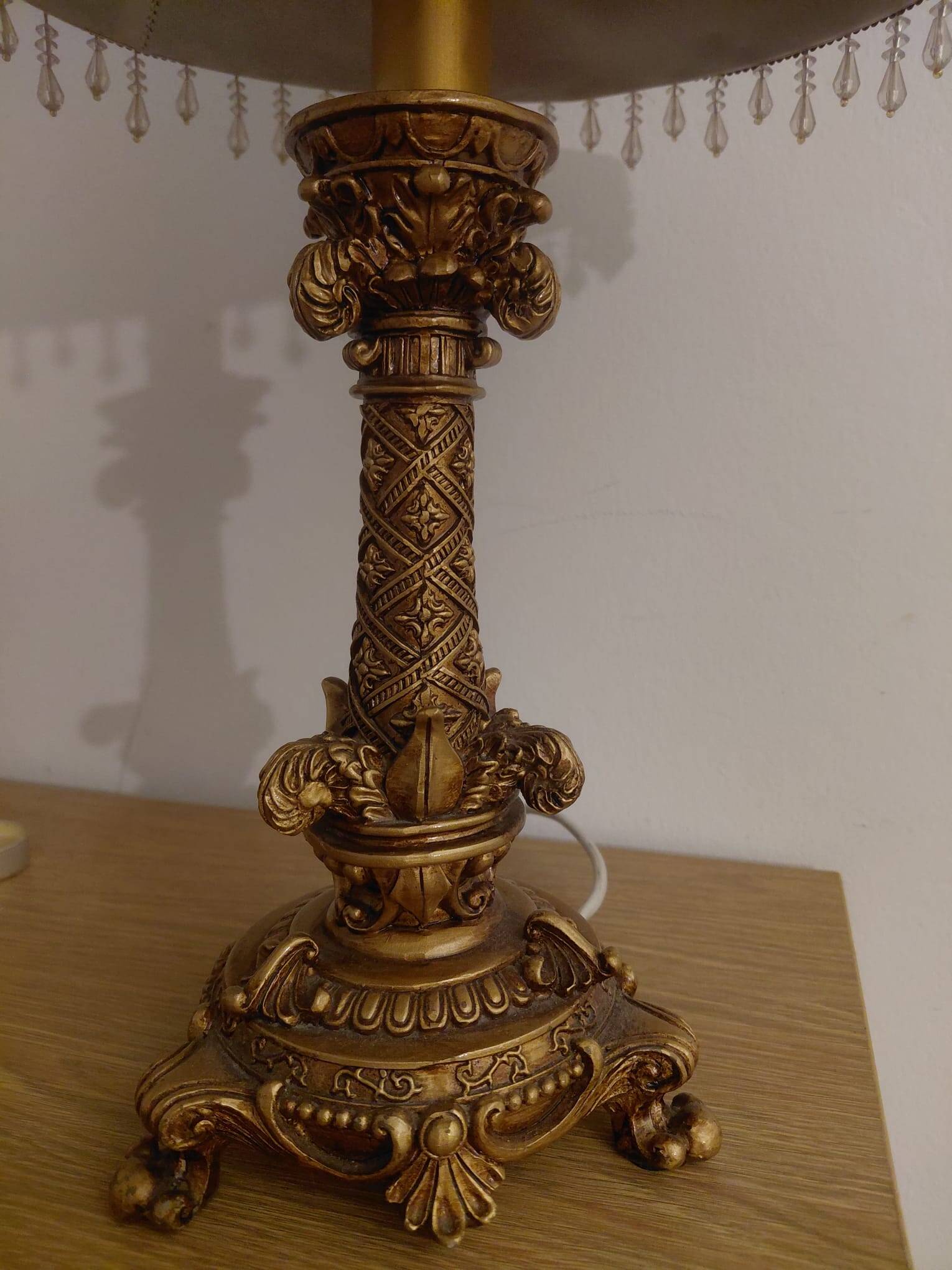 Golden baroque-style table lamp with a shade adorned with pendants.