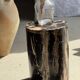 Black petrified wood side table with beige stripes and a semicircular shape.