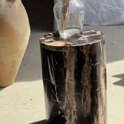 Black petrified wood side table with beige stripes and a semicircular shape.