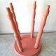 Coral-coloured turned wooden four-legged stool.