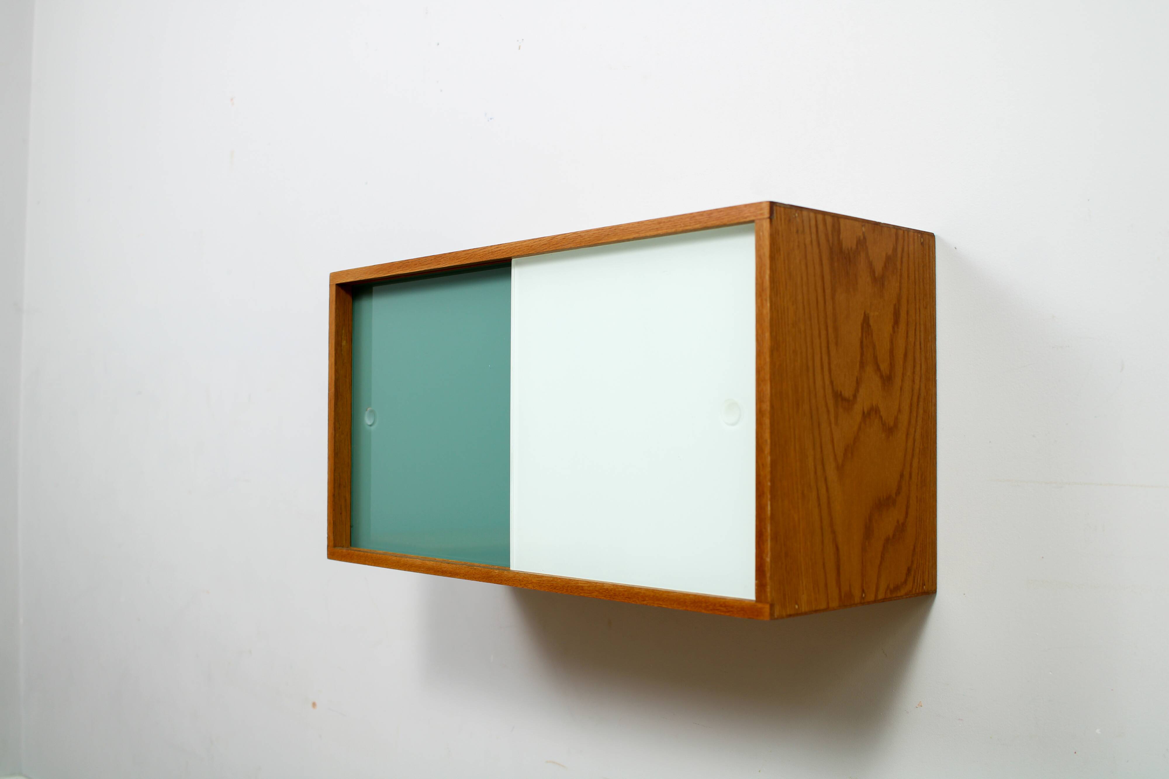 A vintage mid-century wall hung oak cabinet, green & white glass doors