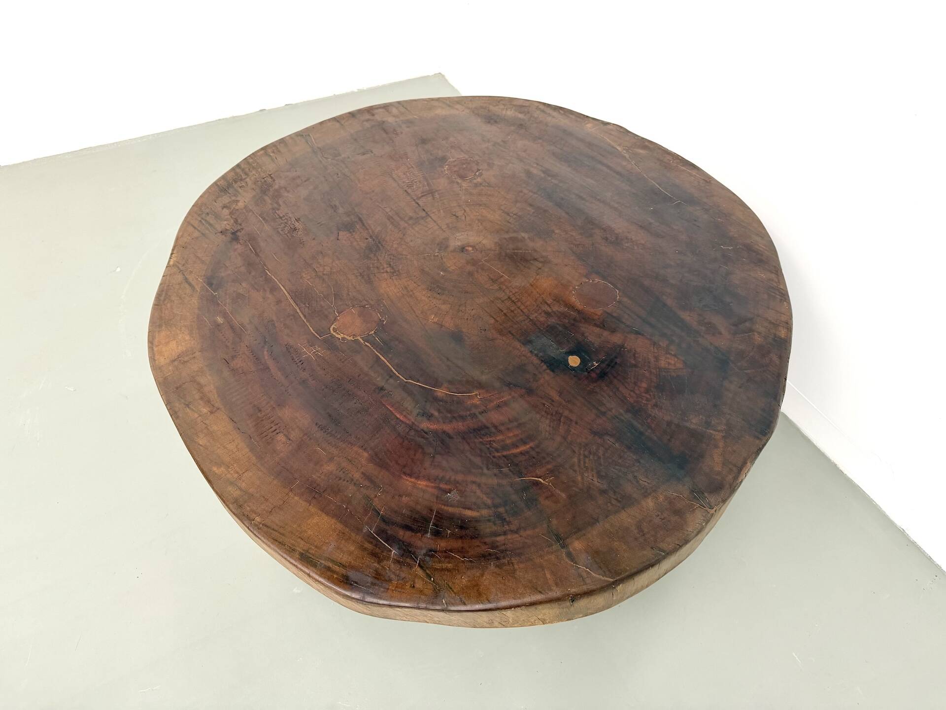 Brutalist coffee table in solid teak, monolithic slab, tripod base.
