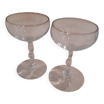 Two small crystal champagne glasses with twisted stems.