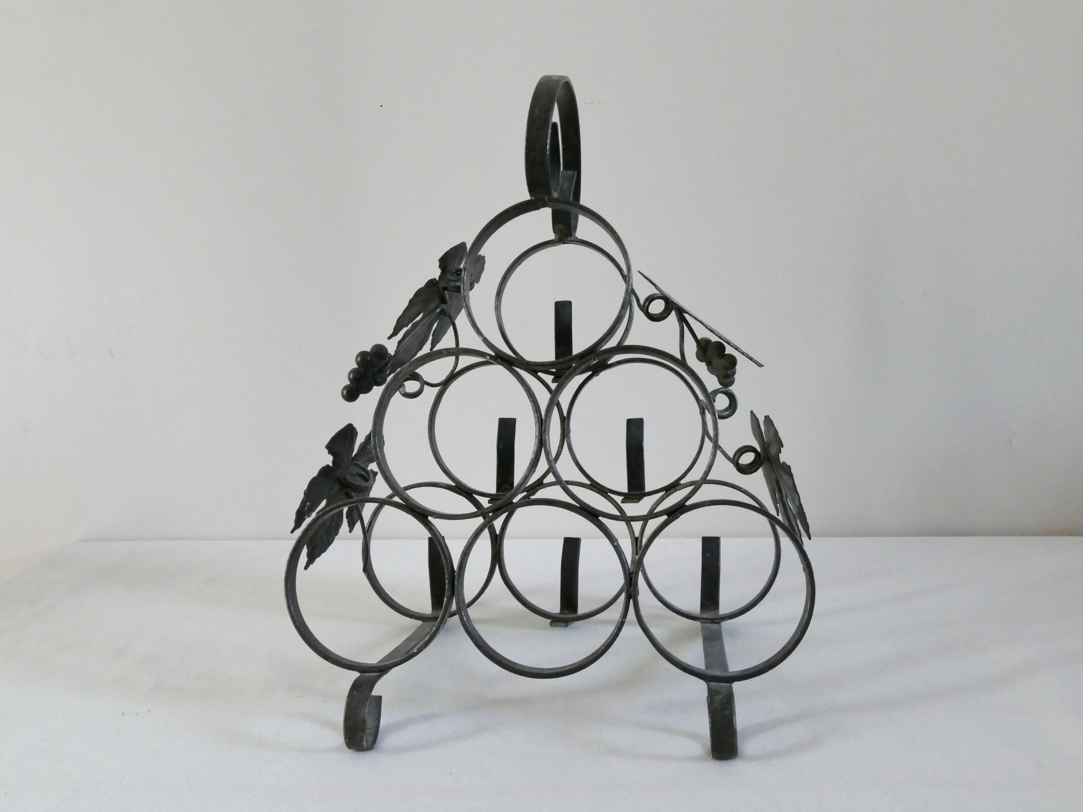 Vintage black wrought iron bottle holder decorated with vine leaves