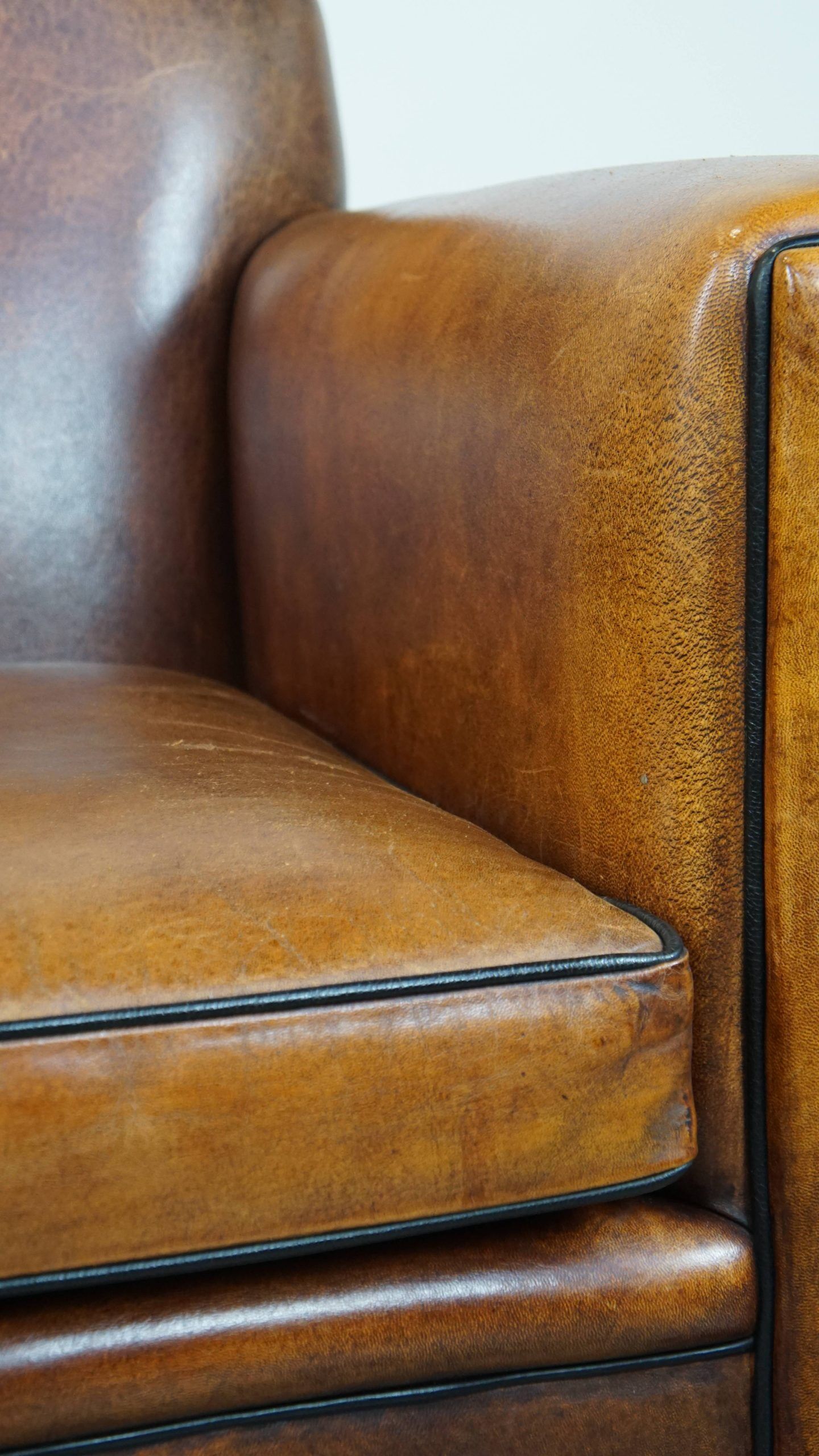 Sheepskin Art Deco design armchair with sleek finish and black piping