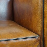 Sheepskin Art Deco design armchair with sleek finish and black piping