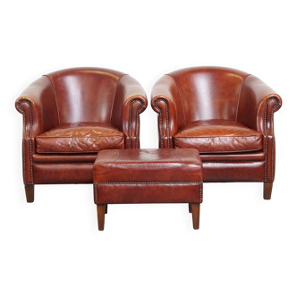 Paire de fauteuils club en cuir de vachette cognac et pouf assorti